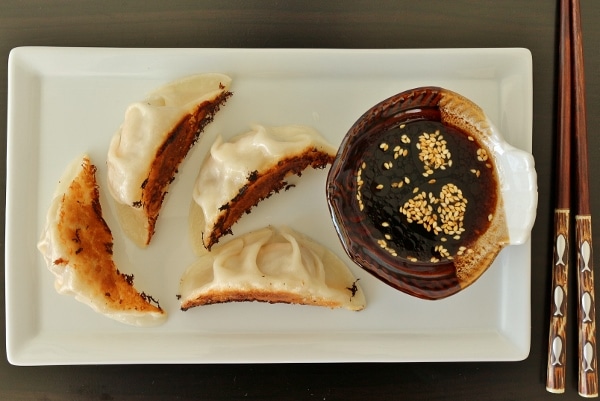 overhead view of a plate of fried dumplings with dipping sauce