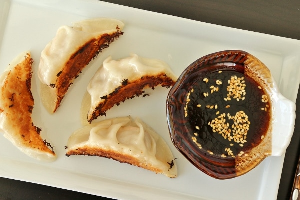 overhead view of pan-fried dumplings with a sesame-soy dipping sauce