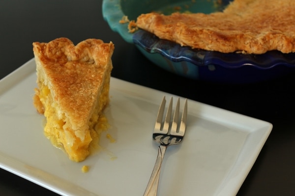 a slice of pineapple pie next to a pie dish filled with pie