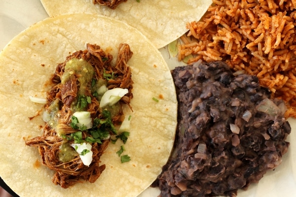 Braised chicken taco served with refried black beans and Mexican rice