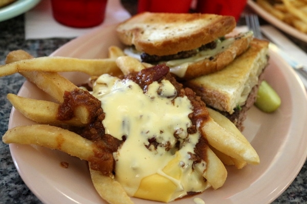 a closeup of chili cheese fries next to a burger