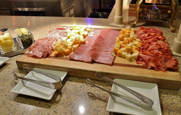 a variety of cold cuts and cheeses on a buffet