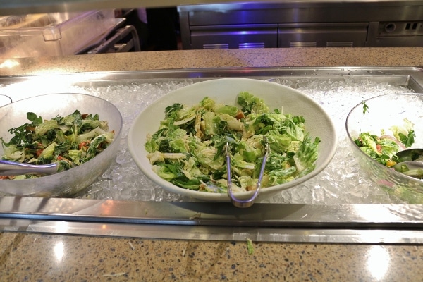 several green salads on a buffet