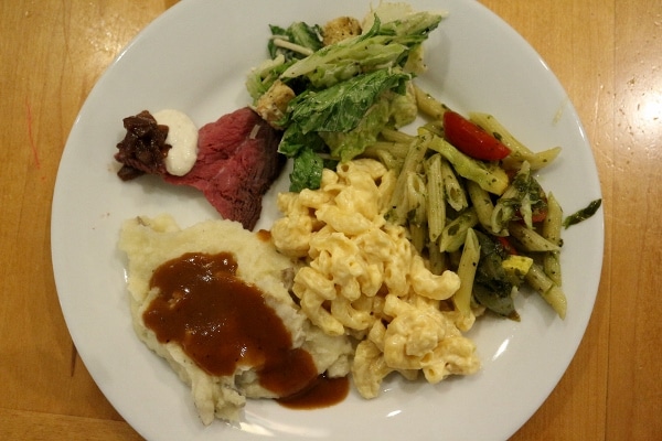 roast beef with salad, mashed potatoes, and pasta on a white plate