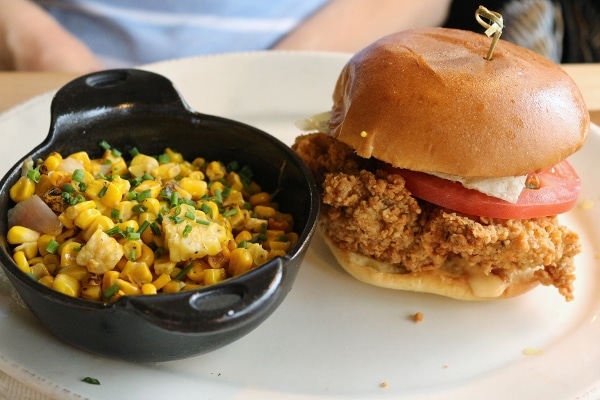 a fried chicken sandwich with succotash on a plate