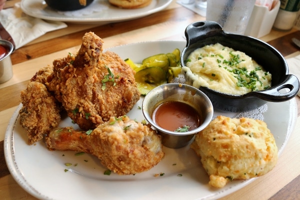 a plate of fried chicken with mashed potatoes and a biscuit