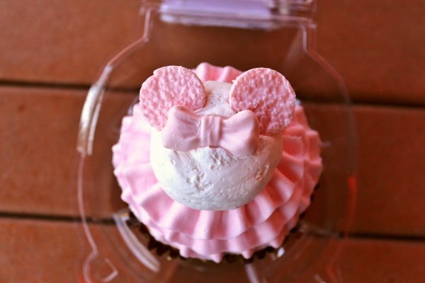 a cupcake with pink frosting in a plastic container