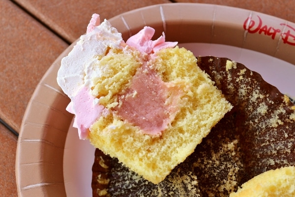 a cross section of a yellow cupcake with pink filling and frosting