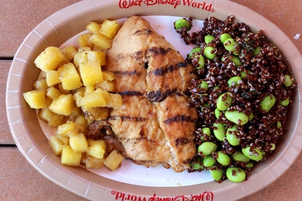 A plate grilled chicken with quinoa salad and pineapple