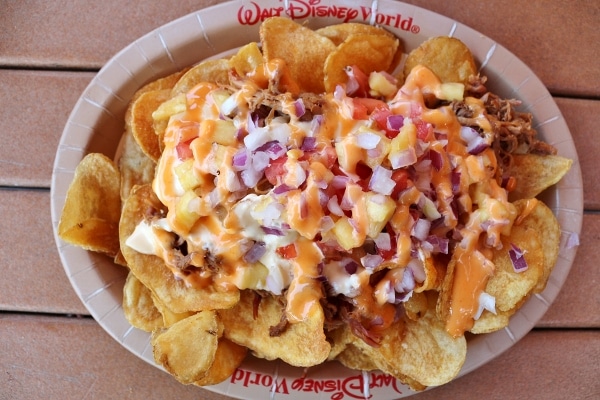 a plate of nachos with pulled pork and pineapple