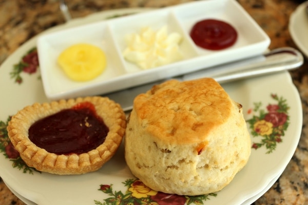 A close up of a scone and small raspberry jam tart