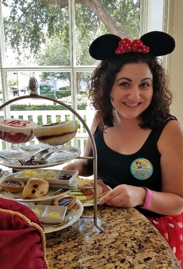 A woman sitting at a table with a plate of food at afternoon tea