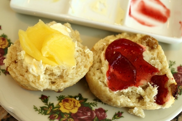 a halved scone topped with clotted cream, jam, and lemon curd