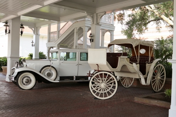 A close up of a carriage and an antique car