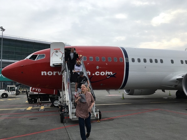 an airplane sitting on the tarmac at an airport with people climbing down the stairs