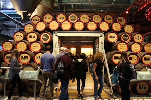 people walking through a doorway framed by beer barrels