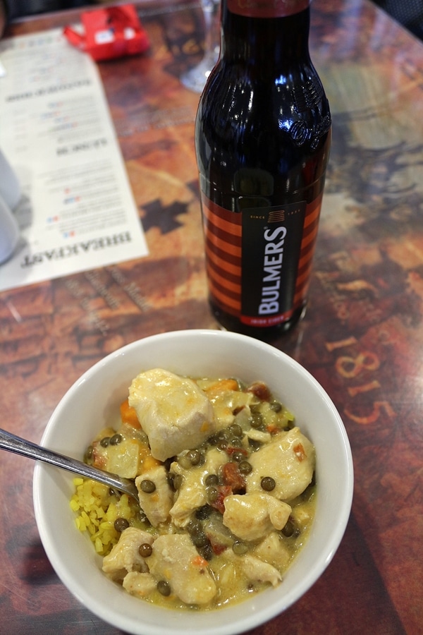 A bowl of food and a bottle of hard cider on a table