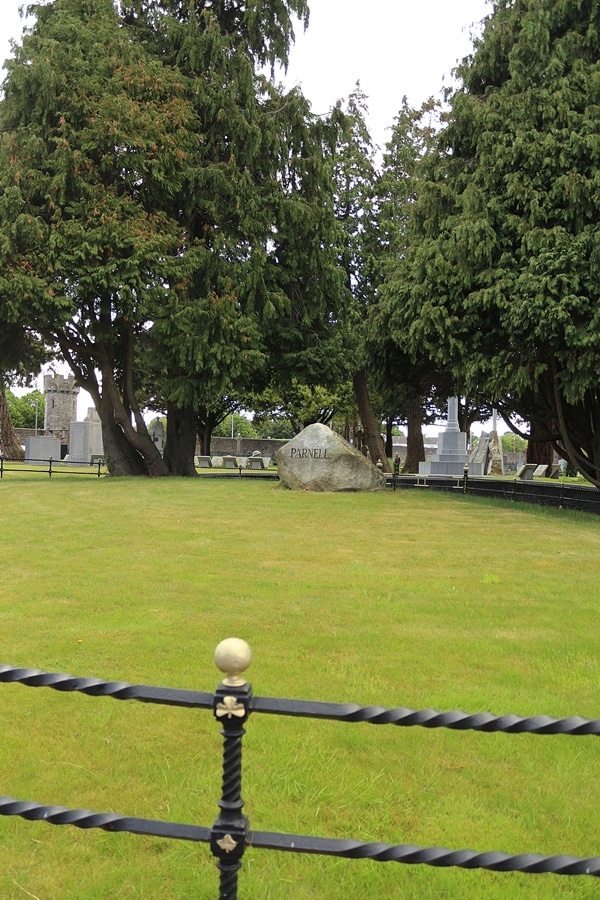 a rock marking a grave inside a large green space
