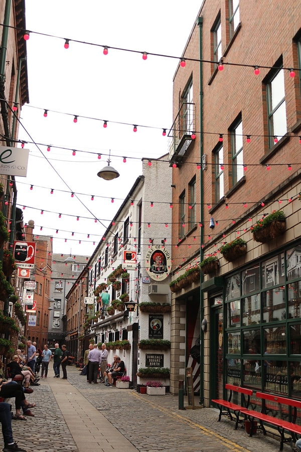 a narrow street with red lights strung up across it