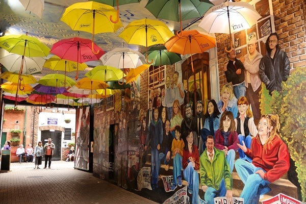 umbrellas hanging in a tunnel painted with murals