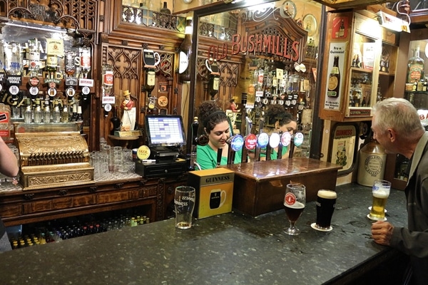 A person standing behind the bar filling a drink