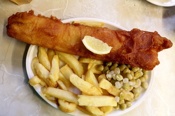 A plate of fish and chips with peas