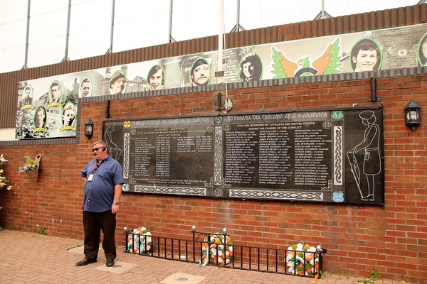 A man standing in front of a brick and metal monument