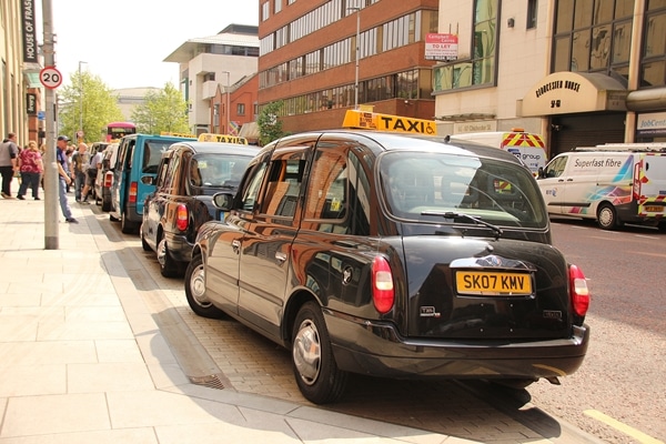 a row of Black Taxis parked on the street in Belfast