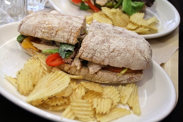 A sandwich cut in half on a plate with ruffled potato chips