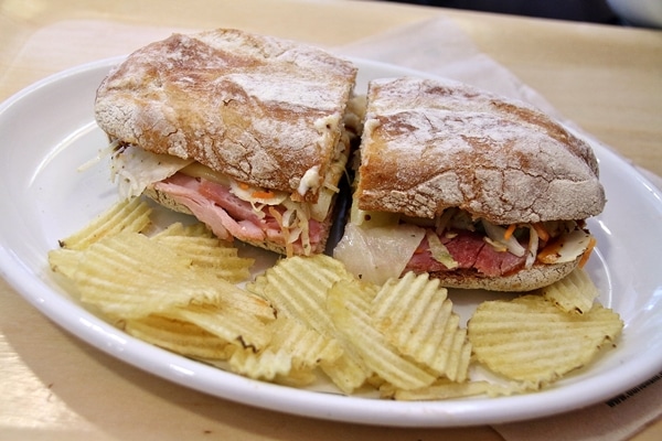 A sandwich cut in half on a plate with potato chips