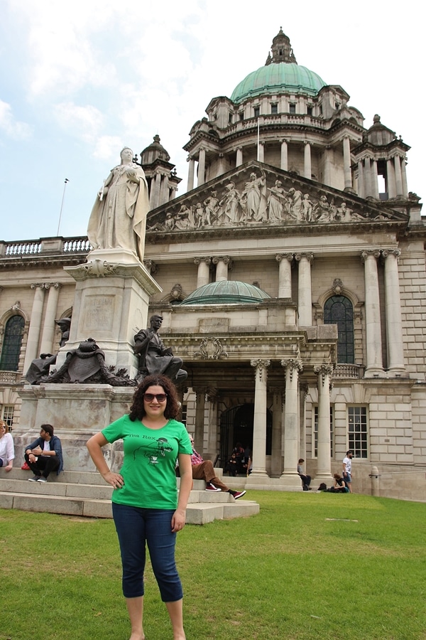 A person posing in front of Queen Victoria\'s statue and Belfast City Hall