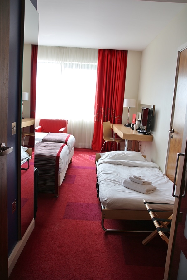 a hotel room with 2 beds and a folding cot