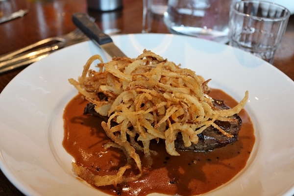 a piece of cooked meat topped with fried onions