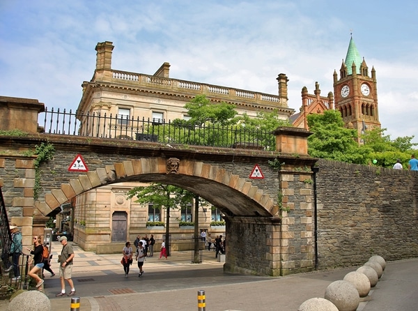 A group of people walking under a stone archway