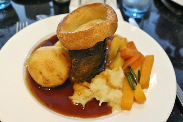 A roasted piece of meat with brown sauce and vegetables