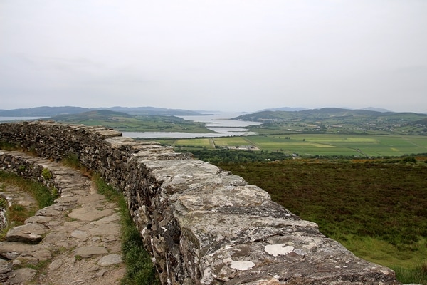 the rocky wall of a fort overlooking green fields