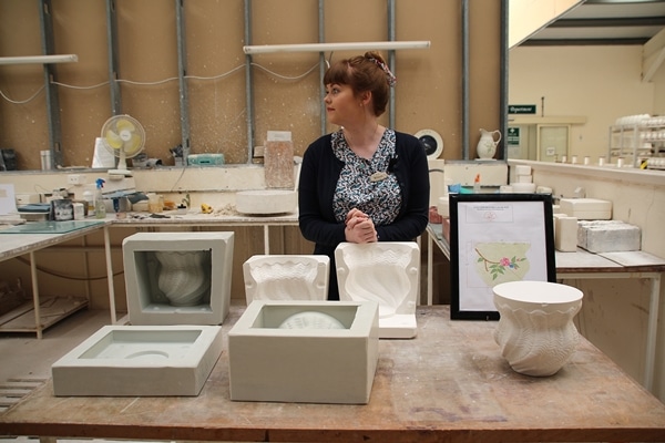 a woman behind a pottery display