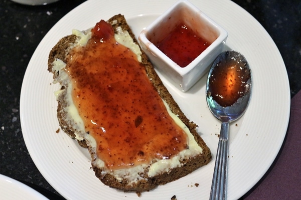 a slice of brown bread topped with butter and jam