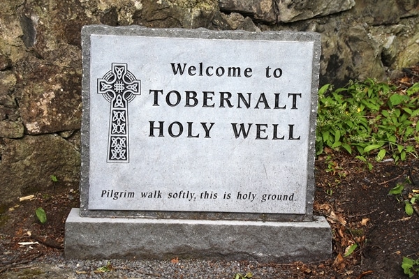 A sign on a rock that says Welcome to Tobernalt Holy Well