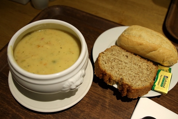 a bowl of chowder next to a plate of bread