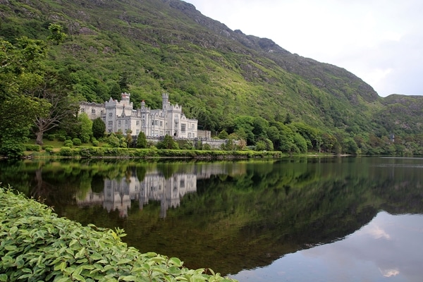 Kylemore Abbey reflected in a pond, surrounded by mountains