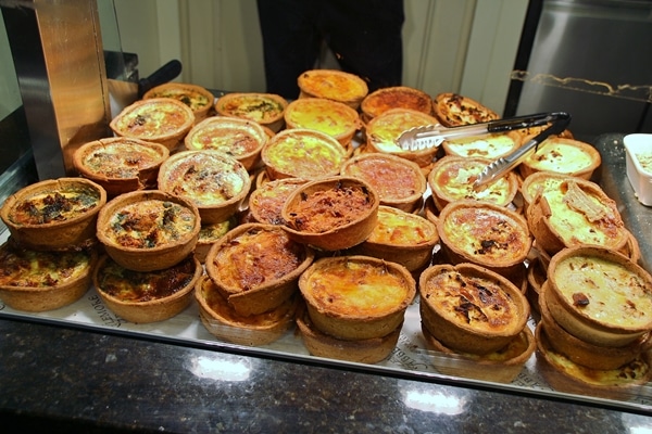 A glass display case featuring individual quiches