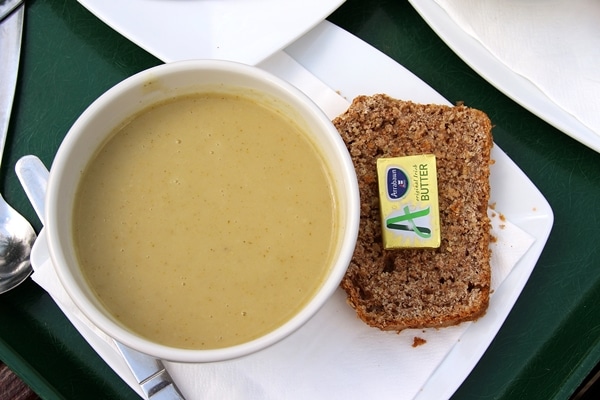 a cup of soup with brown bread on the side