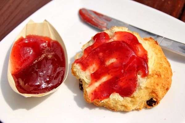 half a scone topped with butter and jam