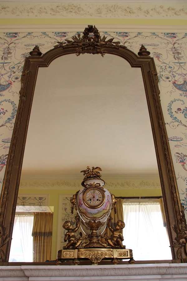 a mirror with an ornate clock in front of it