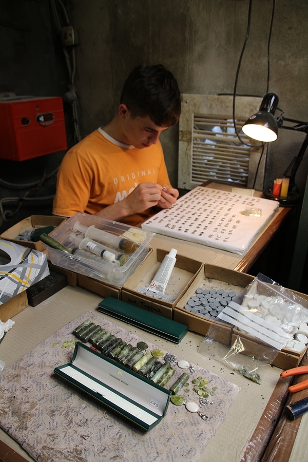 A person sitting in a workshop making jewelry