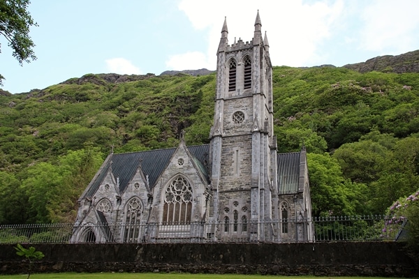 A church with a large tower on top of a lush green field