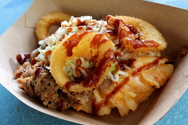 A close up of macaroni and cheese with pulled pork and onion rings