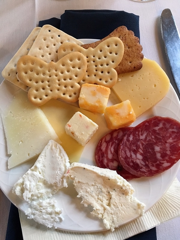 A plate of cheese, crackers, and cured meat