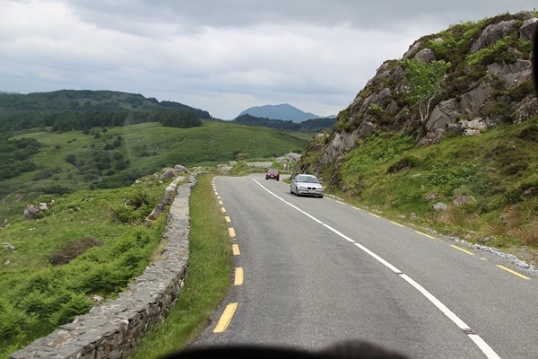 A long road with grass on the side of a mountain